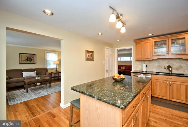 a kitchen with granite countertop a stove a sink dishwasher a refrigerator with wooden cabinets and floor