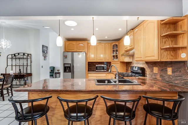 a kitchen with stainless steel appliances granite countertop a table chairs sink and cabinets