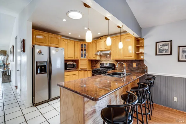 a kitchen with stainless steel appliances granite countertop a table chairs sink and refrigerator