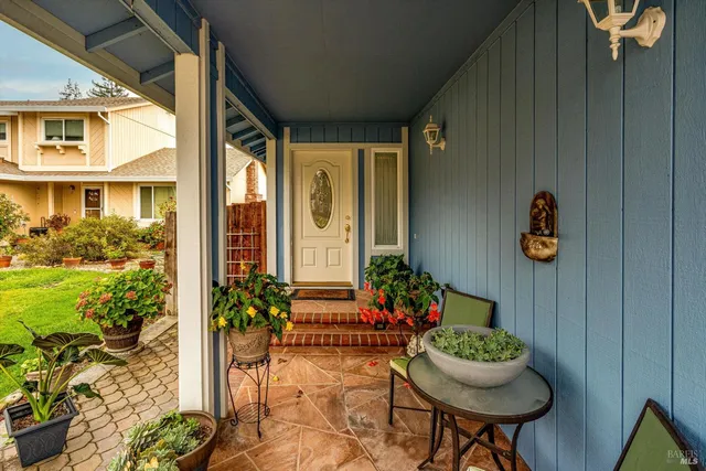 a porch with a table and chairs and potted plants