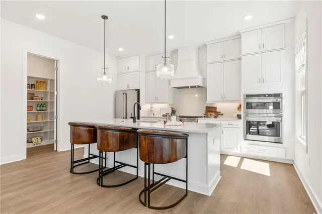 a kitchen with stainless steel appliances granite countertop a sink a stove a refrigerator and wooden floor