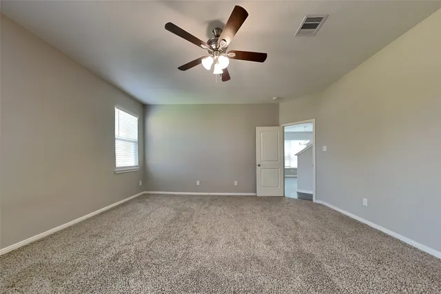 an empty room with ceiling fan and window