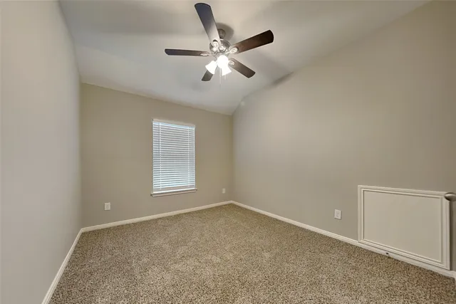 an empty room with ceiling fan and windows