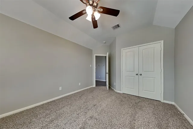 a view of an empty room and chandelier fan