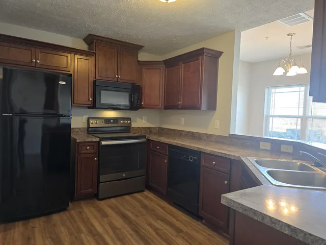 an empty room with a chandelier fan and windows