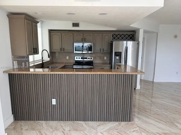 a kitchen with stainless steel appliances kitchen island granite countertop a refrigerator a stove a sink dishwasher and wooden floor
