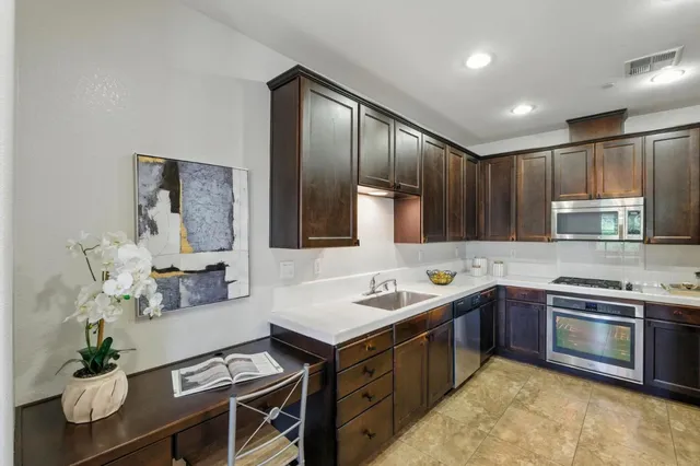 a kitchen with stainless steel appliances granite countertop a sink counter space cabinets and a stove