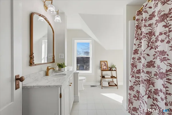 a bathroom with a granite countertop toilet sink and mirror