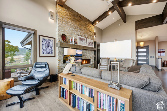 1130 Pace Road Park City, UT 84098 - Photo 16 of 73 Vaulted ceiling with exposed wood beams, stone-clad fireplace, wood-finish flooring, and large window overlooking natural scenery