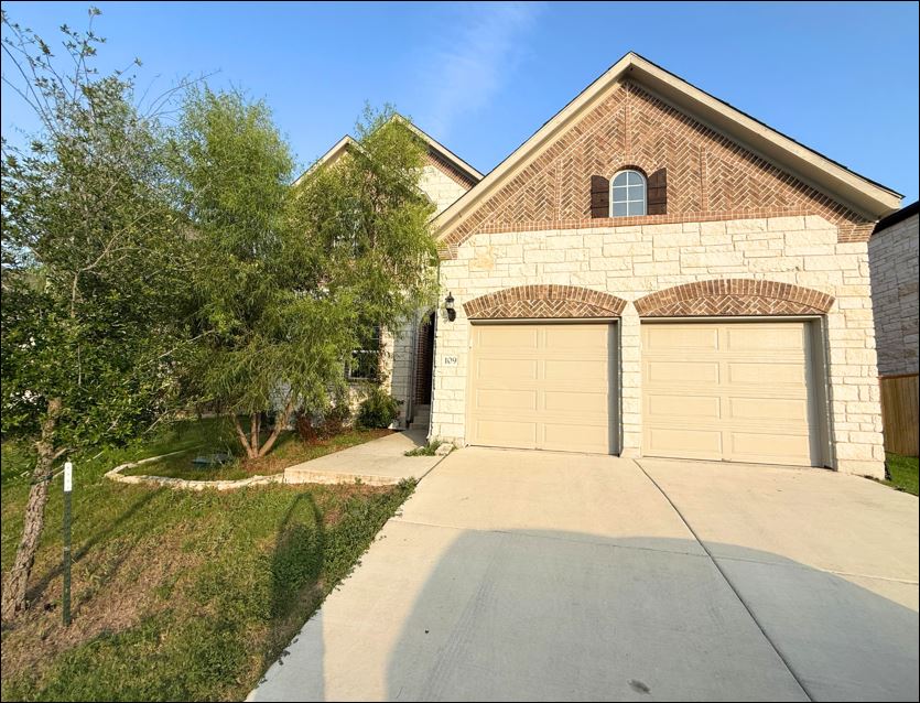 A charming facade combines stone and brickwork with twin arched garage doors, creating delightful curb appeal.
