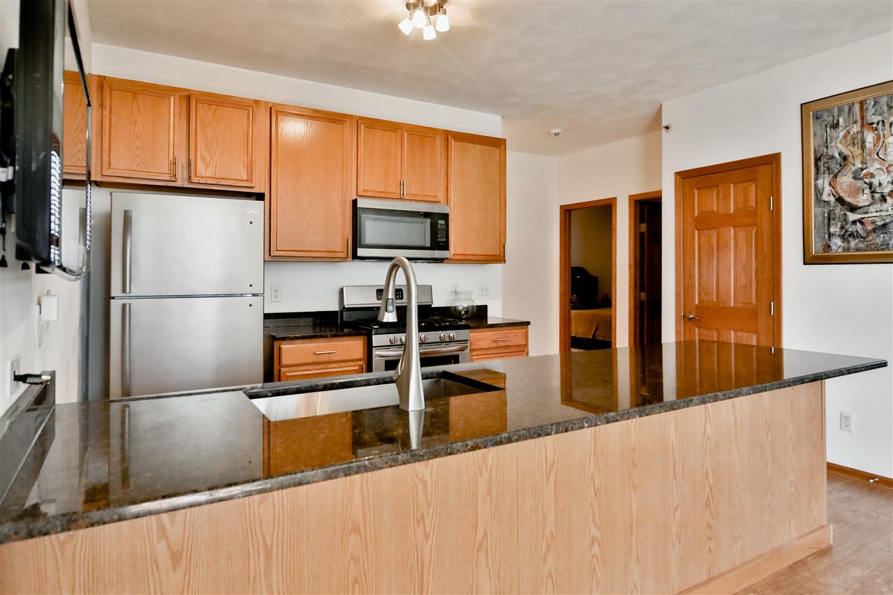 10135 Monarch Road, Unit 3 Roscoe, IL 61073 - Photo 11 of 20 a kitchen with stainless steel appliances granite countertop a refrigerator a stove and a sink with wooden floor