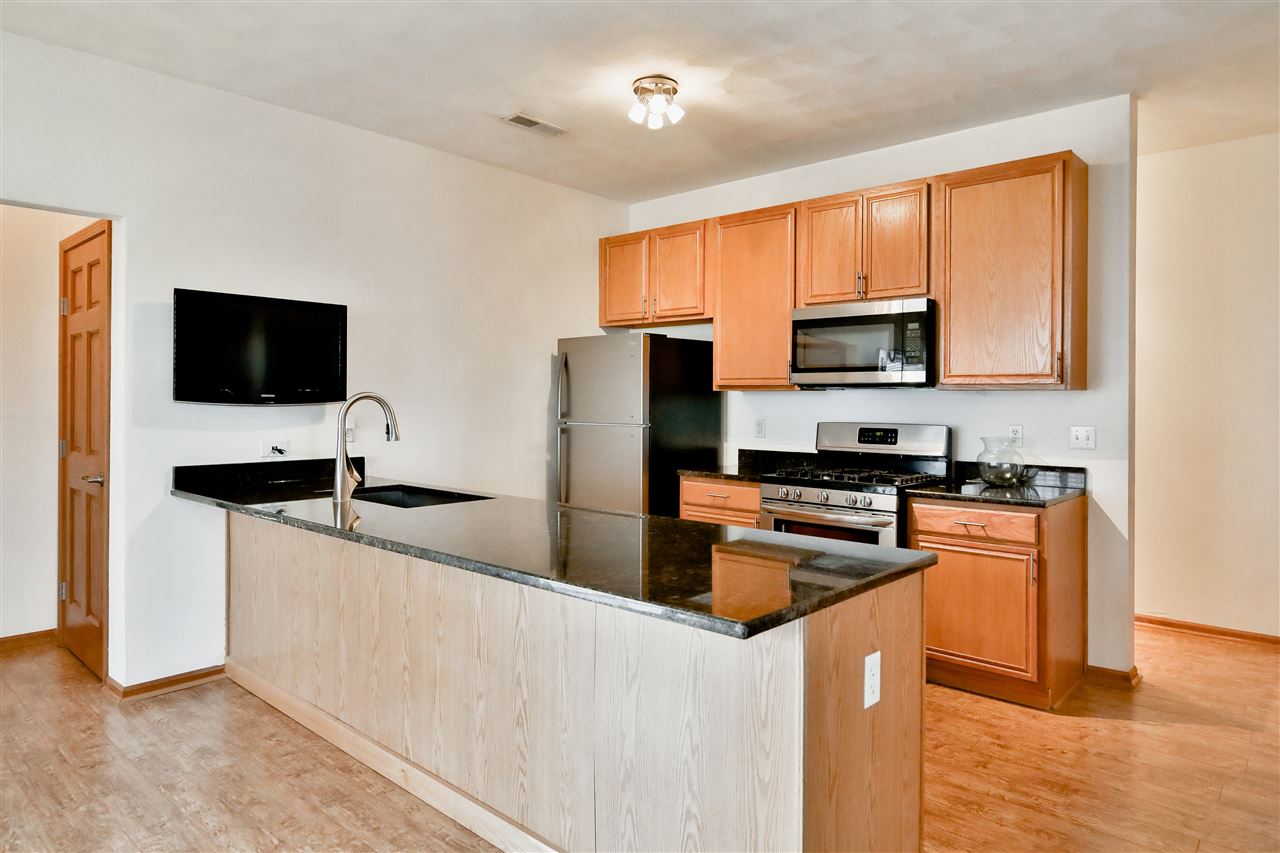 10135 Monarch Road, Unit 3 Roscoe, IL 61073 - Photo 9 of 20 a kitchen with stainless steel appliances granite countertop a stove a sink and a refrigerator