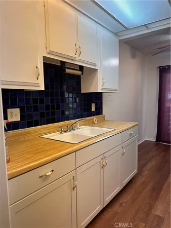 a room with kitchen island a sink and white cabinets