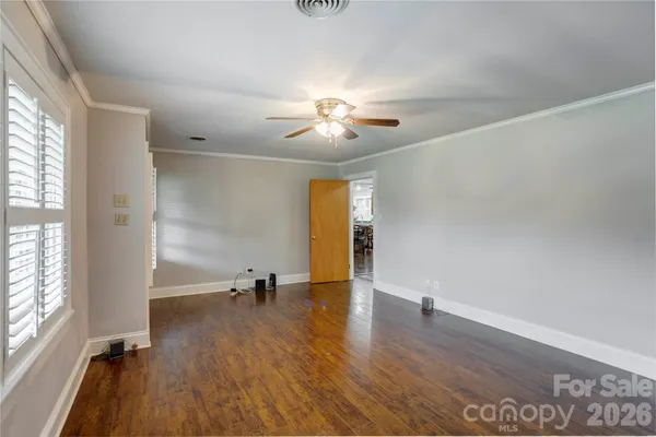 an empty room with wooden floor fireplace and windows