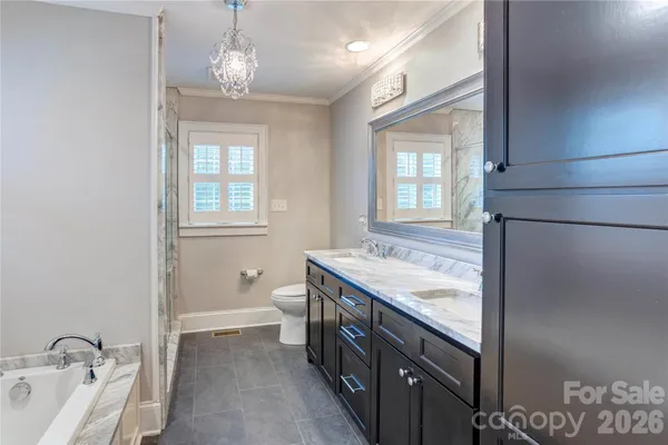 a spacious bathroom with a granite countertop tub a double vanity sink a window and a potted plant