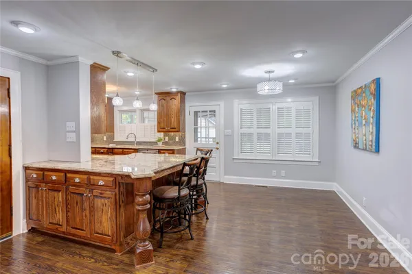 a dining hall with stainless steel appliances granite countertop a stove and a wooden floors