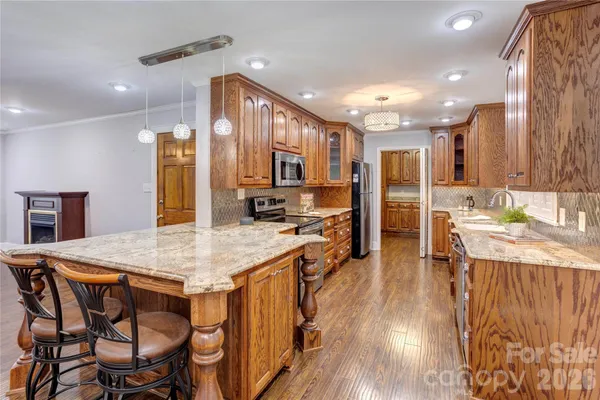 a kitchen with stainless steel appliances kitchen island granite countertop a kitchen island and chairs in it
