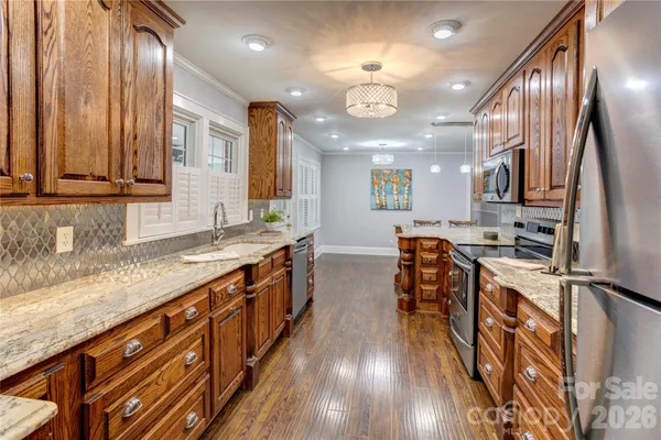 a large kitchen with stainless steel appliances granite countertop a lot of counter space and wooden floors