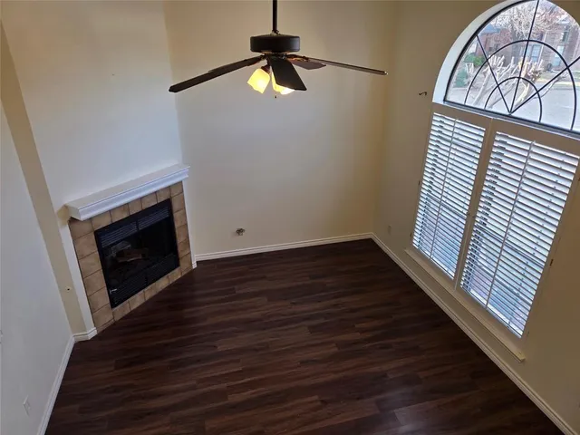 a view of an empty room with wooden floor fireplace and a window