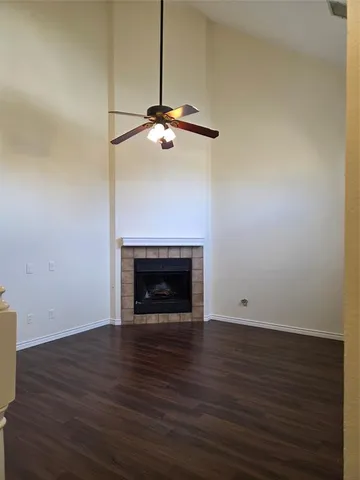 a view of an empty room with wooden floor a fireplace and a window