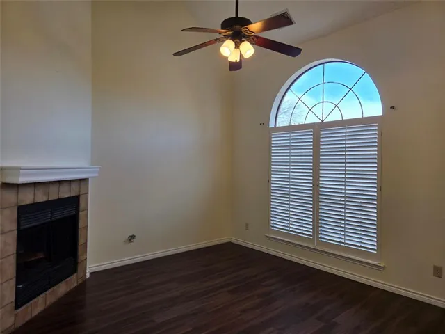 a view of empty room with wooden floor fan and window