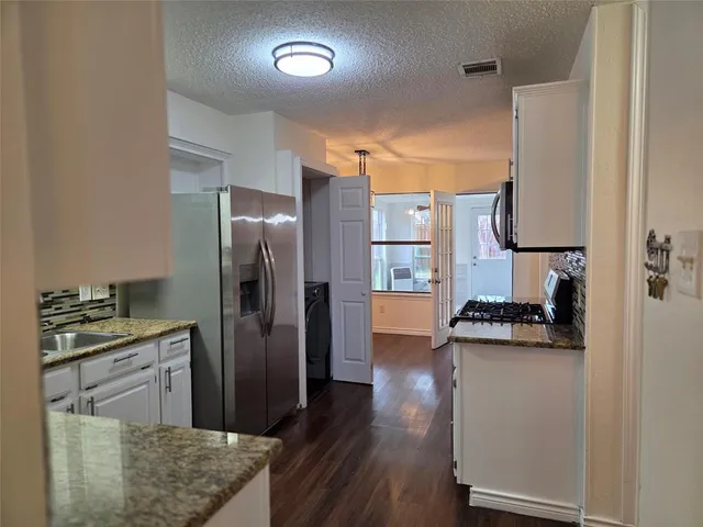 a kitchen with stainless steel appliances granite countertop a refrigerator and a stove