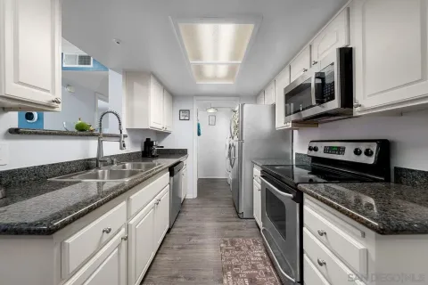 a kitchen with a sink dishwasher and cabinets with wooden floor