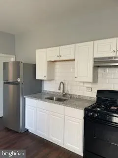 a kitchen with granite countertop white cabinets and refrigerator