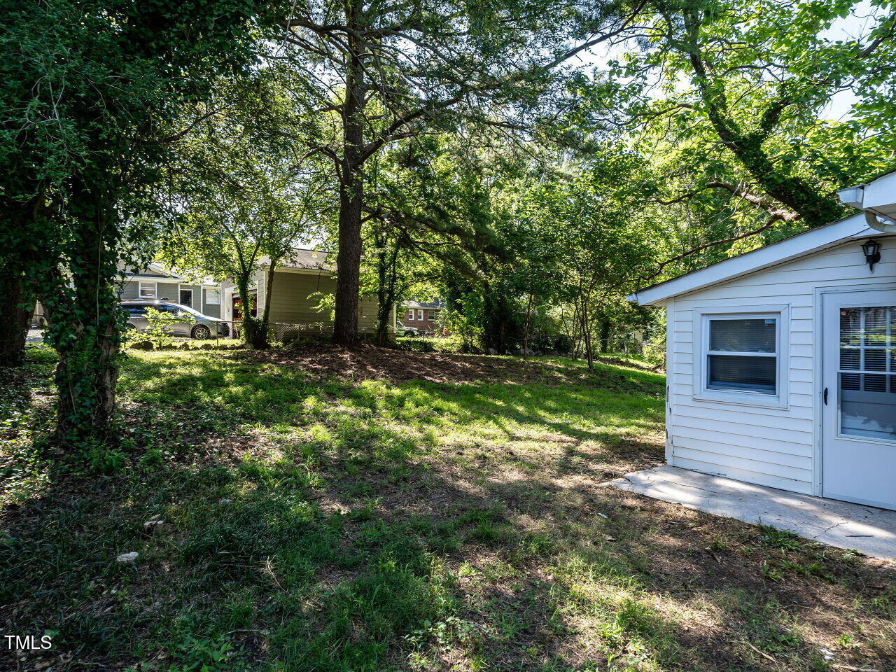 829 Greenwich Street Raleigh, NC 27610 - Photo 26 of 29 a view of a backyard with plants and large tree