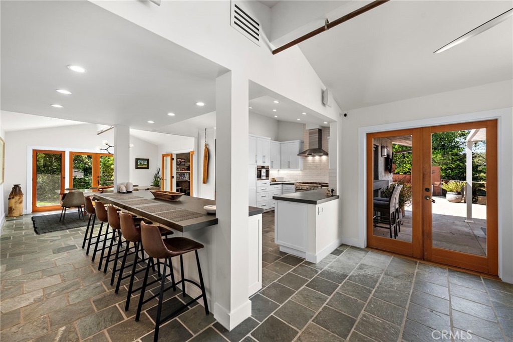 3085 Nestall Road Laguna Beach, CA 92651 - Photo 9 of 33 a kitchen with stainless steel appliances kitchen island granite countertop a refrigerator a stove a sink a dining table and chairs with wooden floor