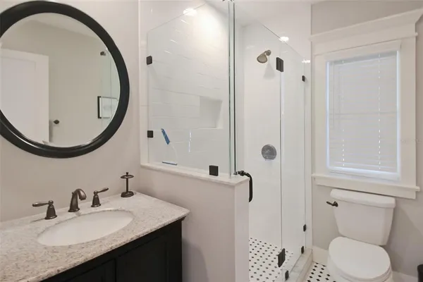 a bathroom with a granite countertop sink toilet and a mirror