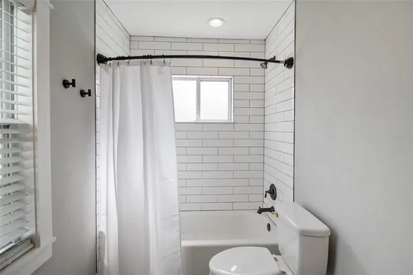 a bathroom with a granite countertop bathtub shower and toilet