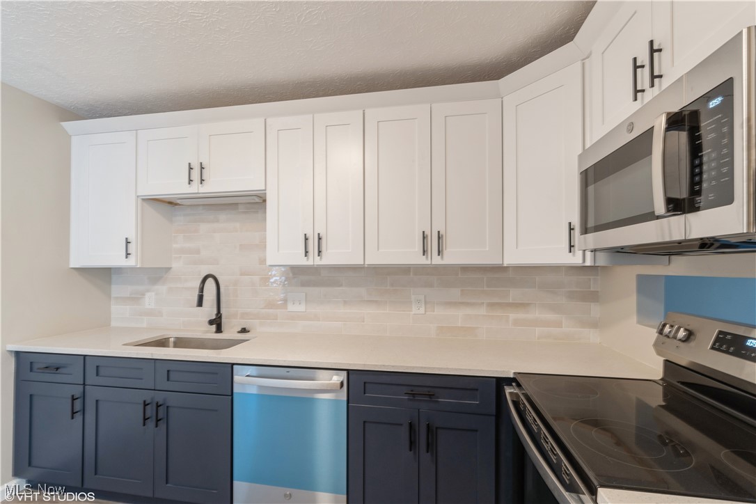 3725 Mayfield Road Cleveland Heights, OH 44121 - Photo 8 of 16 Kitchen featuring white cabinets, appliances with stainless steel finishes, decorative backsplash, and sink