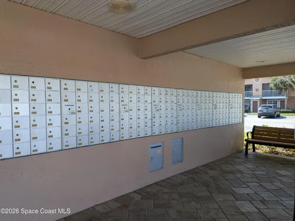 a view of empty room with wooden floor and kitchen