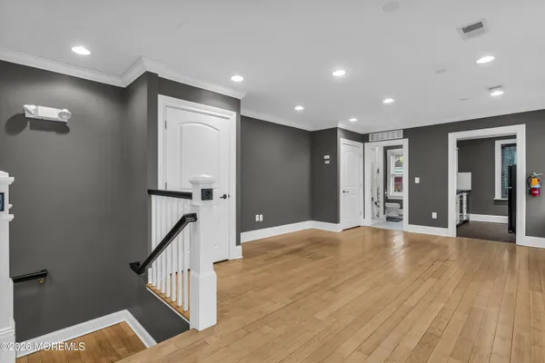 a view of an empty room with wooden floor and windows