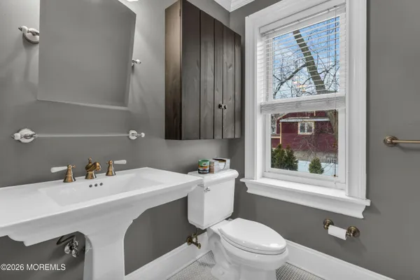 a bathroom with a toilet sink a window and shower