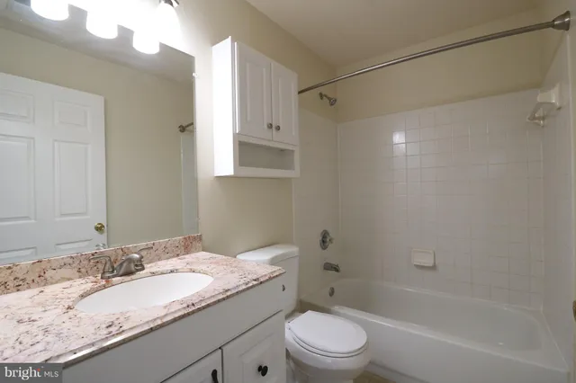 a bathroom with a granite countertop sink a toilet and shower