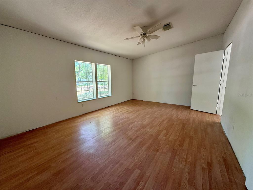 21471 Northwest 172nd Road High Springs, FL 32643 - Photo 8 of 26 an empty room with wooden floor chandelier fan and windows