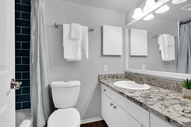 a bathroom with a granite countertop toilet sink and mirror