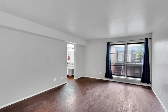 an empty room with wooden floor and window
