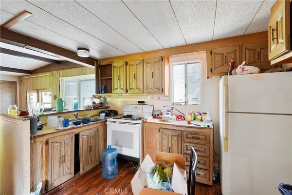 a kitchen with stainless steel appliances a refrigerator a sink dishwasher a stove a dining table and chairs with wooden floor