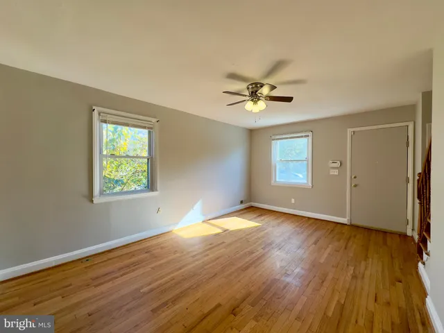 an empty room with wooden floor chandelier and windows