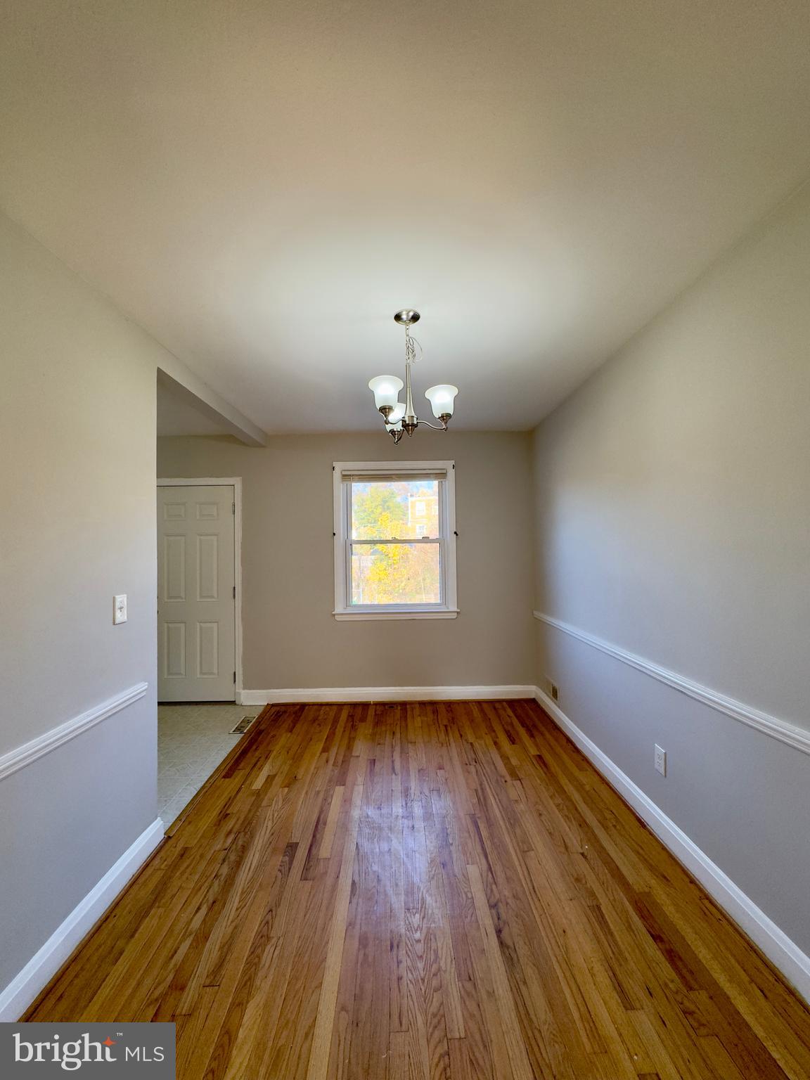 3710 Springwood Avenue Baltimore, MD 21206 - Photo 8 of 24 an empty room with wooden floor chandelier and windows