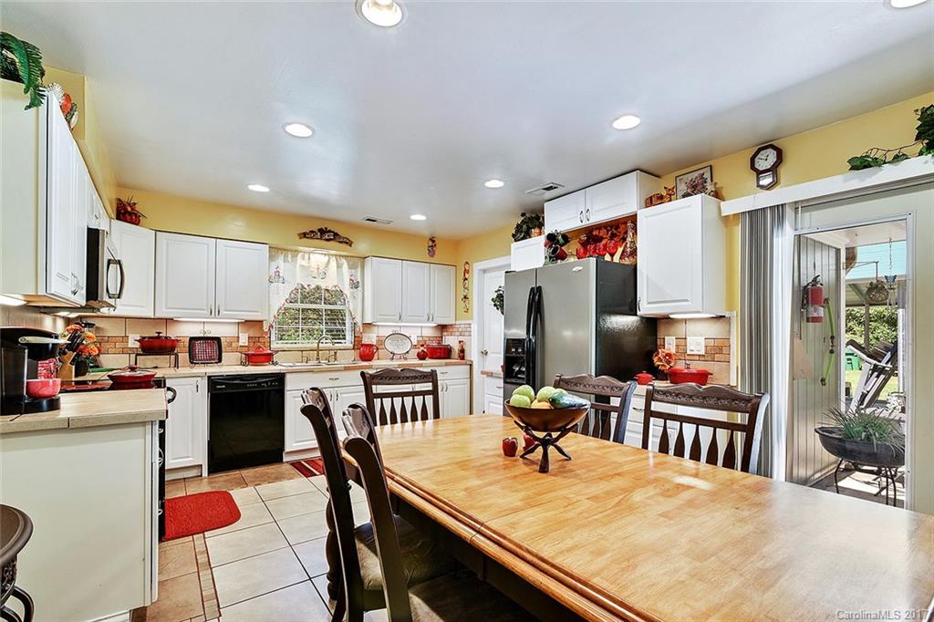 7101 Riding Trail Road, Unit 1 Charlotte, NC 28212 - Photo 4 of 14 a kitchen with stainless steel appliances kitchen island granite countertop a refrigerator oven a stove a sink dishwasher and a dining table with the kitchen view