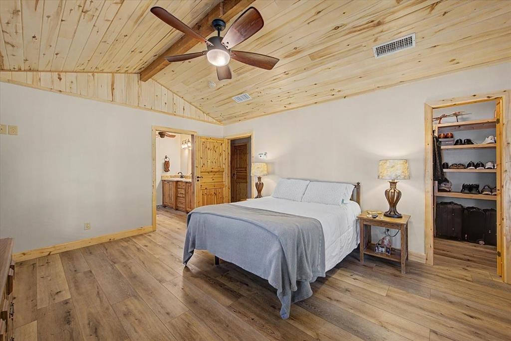 2789 Hanging Tree Road Bowie, TX 76230 - Photo 14 of 40 Vaulted wood-paneled ceiling with exposed beam, wood-finish flooring, built-in open shelving, and a ceiling fan