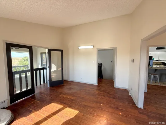 a view of a hallway with wooden floor and a bathroom