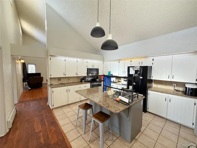 a kitchen with a sink dishwasher stove and white cabinets with wooden floor