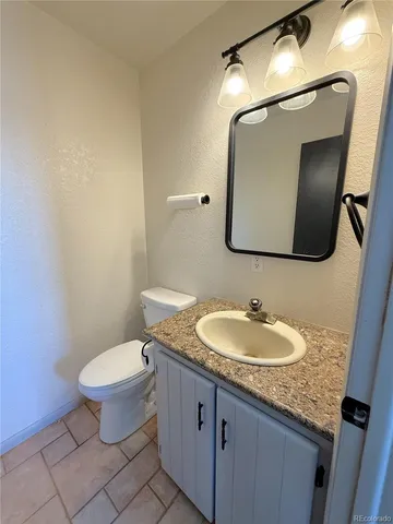 a bathroom with a granite countertop toilet a sink and a mirror