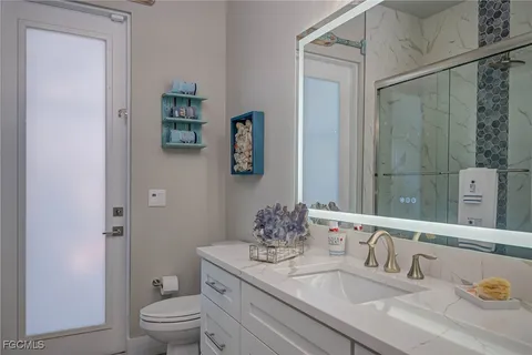 a bathroom with a granite countertop sink a toilet and a mirror