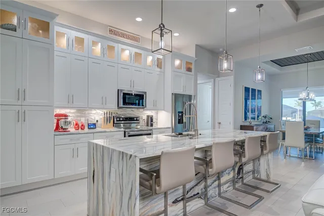 a kitchen with stainless steel appliances kitchen island granite countertop a stove a sink a refrigerator a center island a dining table and chairs
